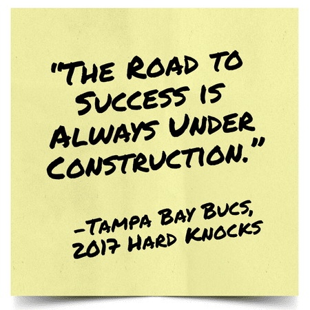 Yellow sticky note with bold black handwritten quote: 'The road to success is always under construction.' — Tampa Bay Buccaneers, 2017 Hard Knocks.